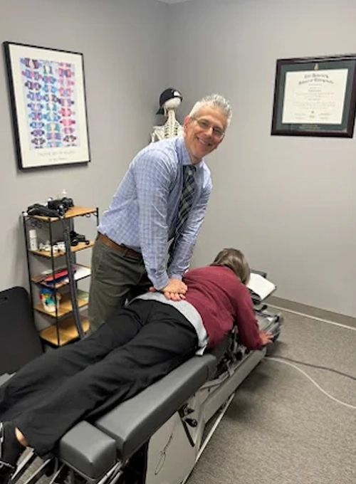 Dr. David DeRosa performing a low back adjustment in a female patient.